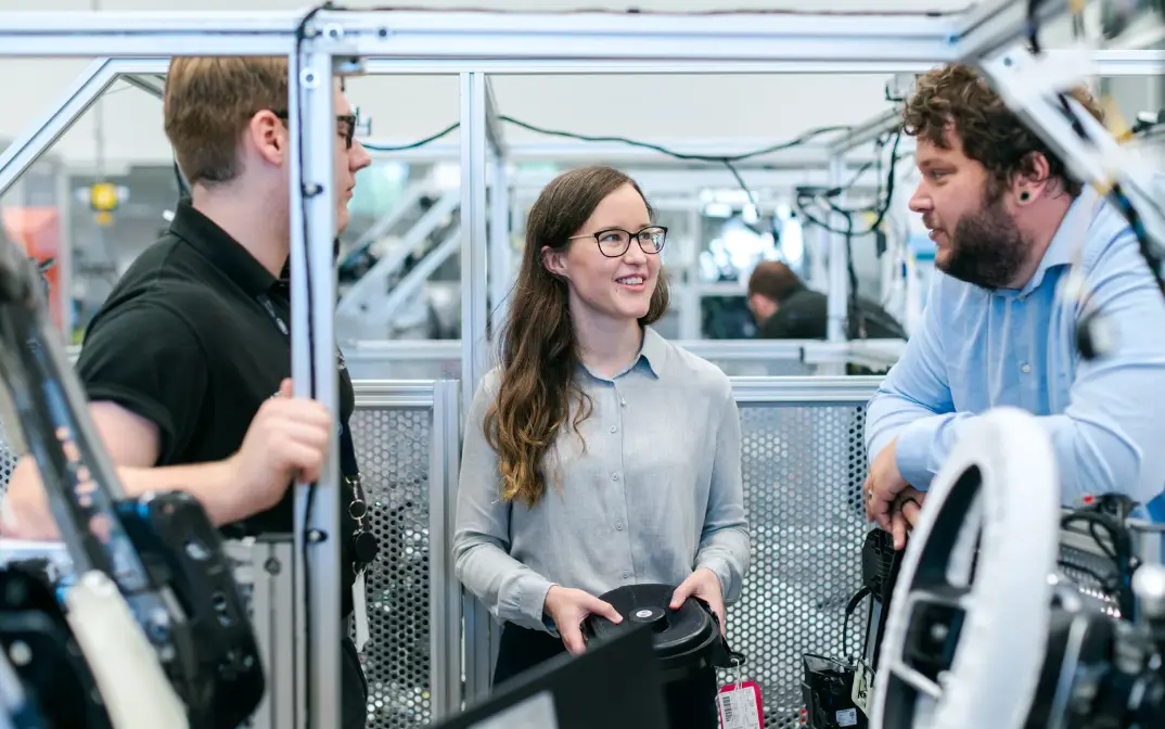 three colleagues having a discussion while the woman is looking at the person in the right.